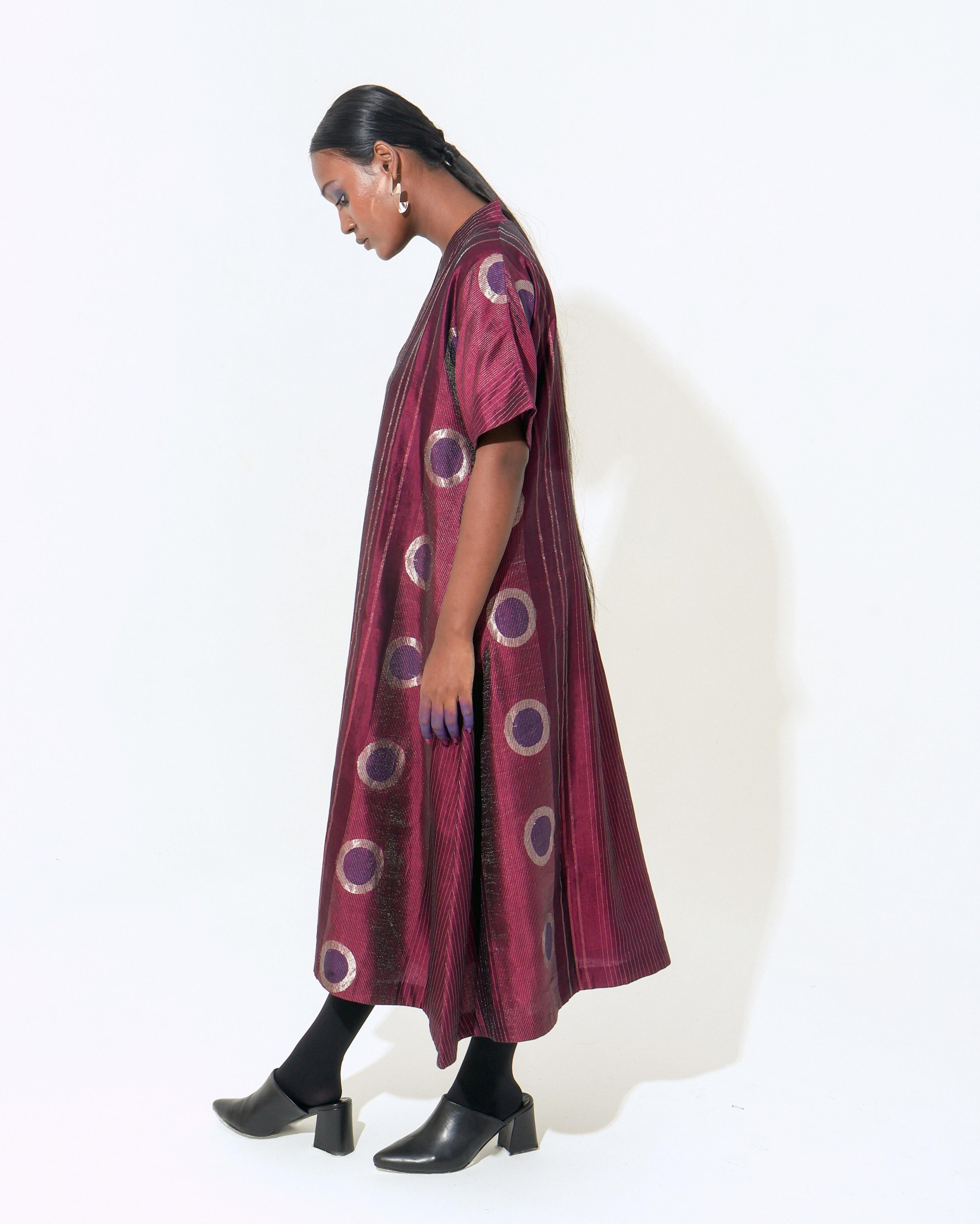 The Shoonyata Neelbindu Dress is crafted from handwoven silk, featuring the intricate Jacquard Jamdani technique with circular motifs across the fabric. Designed with a relaxed A-line silhouette that flows to a midi length, this dress exudes elegance and comfort.