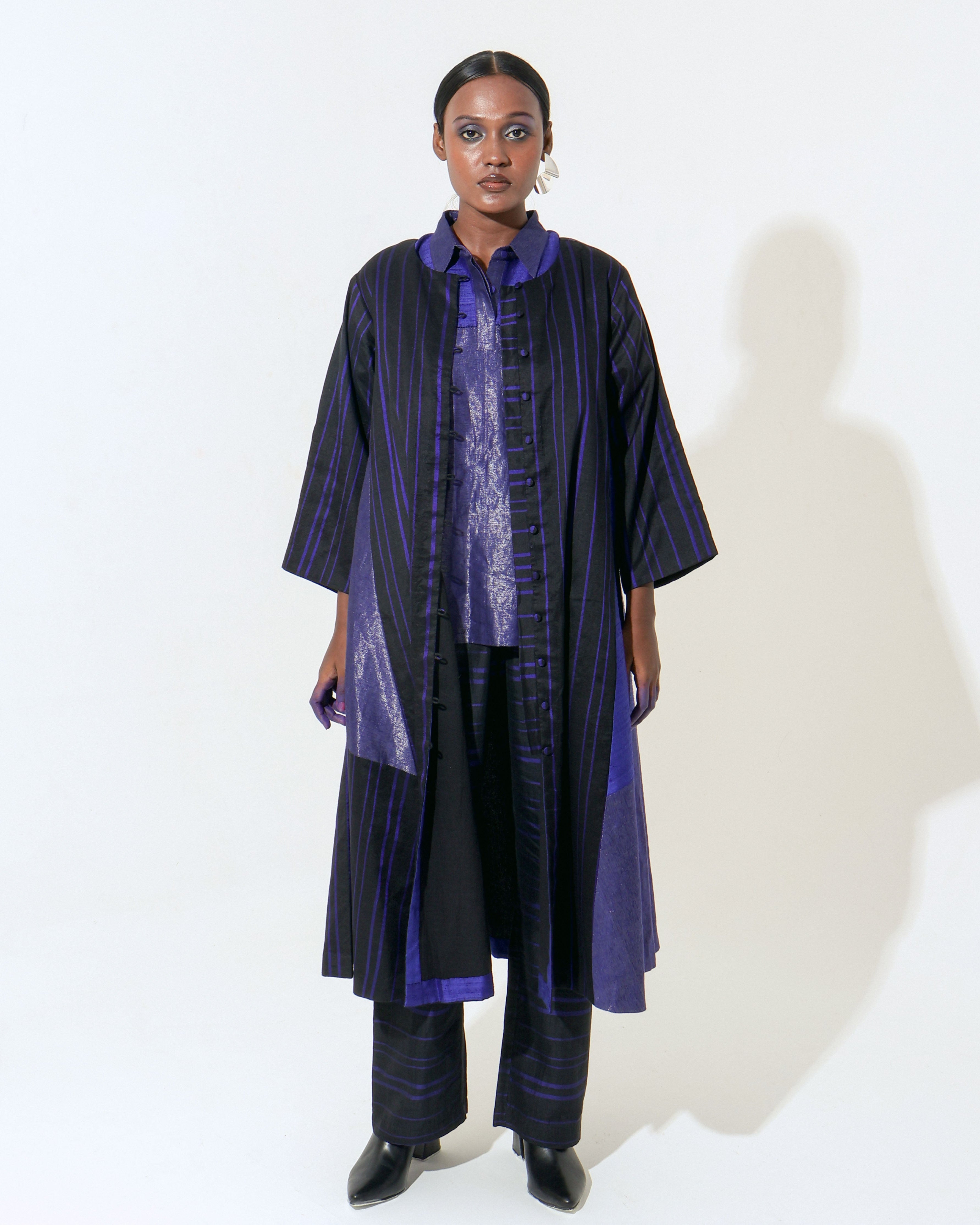 The Shoonyata Hybrid Jacket Dress is a blend of handwoven silk and cotton using the Jacquard Jamdani  technique.The dress has a structured A-line silhouette with a buttoned front, full-length straight sleeves, and a layered band collar..