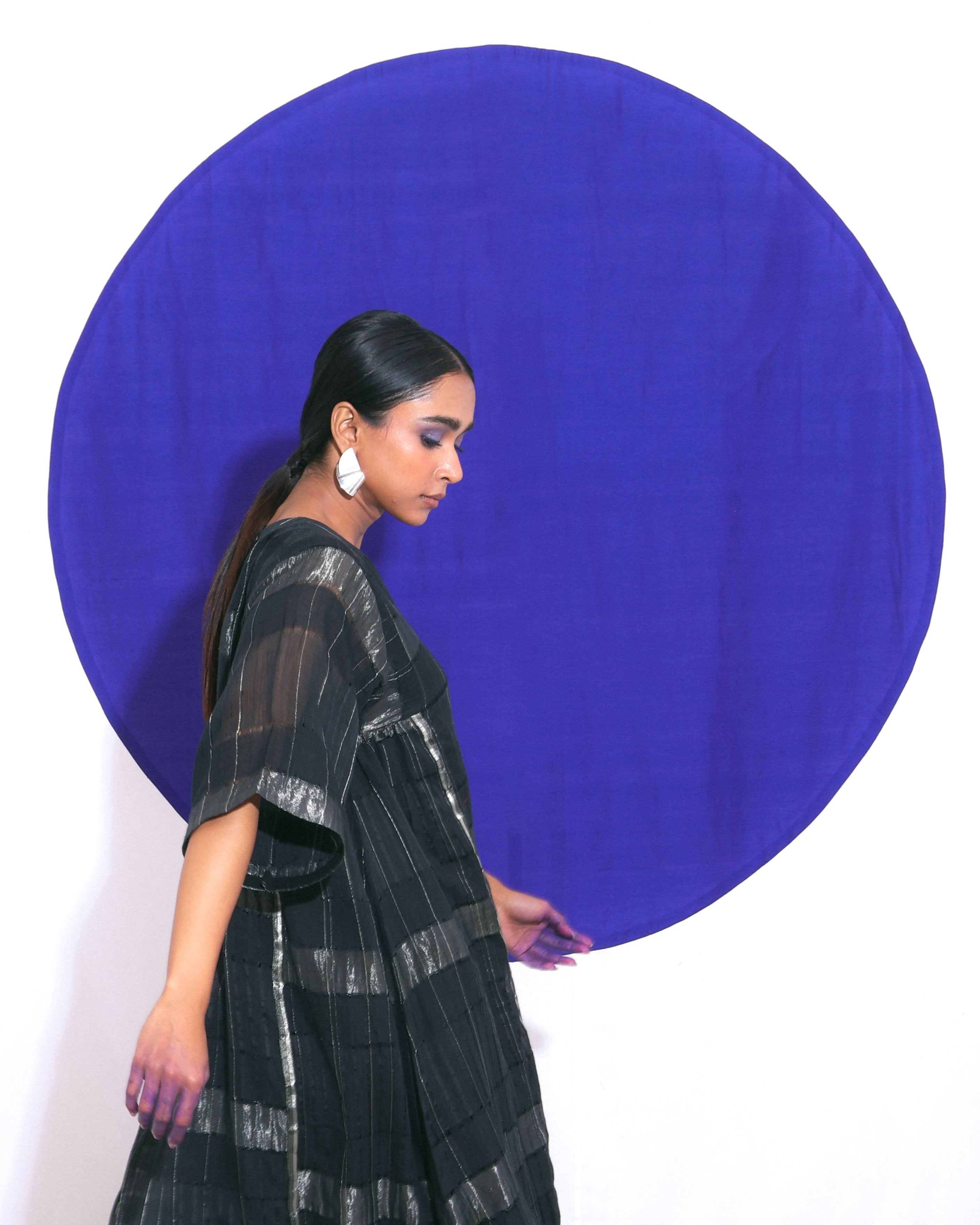 The "Shoonyata Blockstripe Panelled Dress" is an elegant dress made from handwoven silk. It features a round neckline with notched detailing, and wide, three-quarter-length sleeves for a relaxed fit.