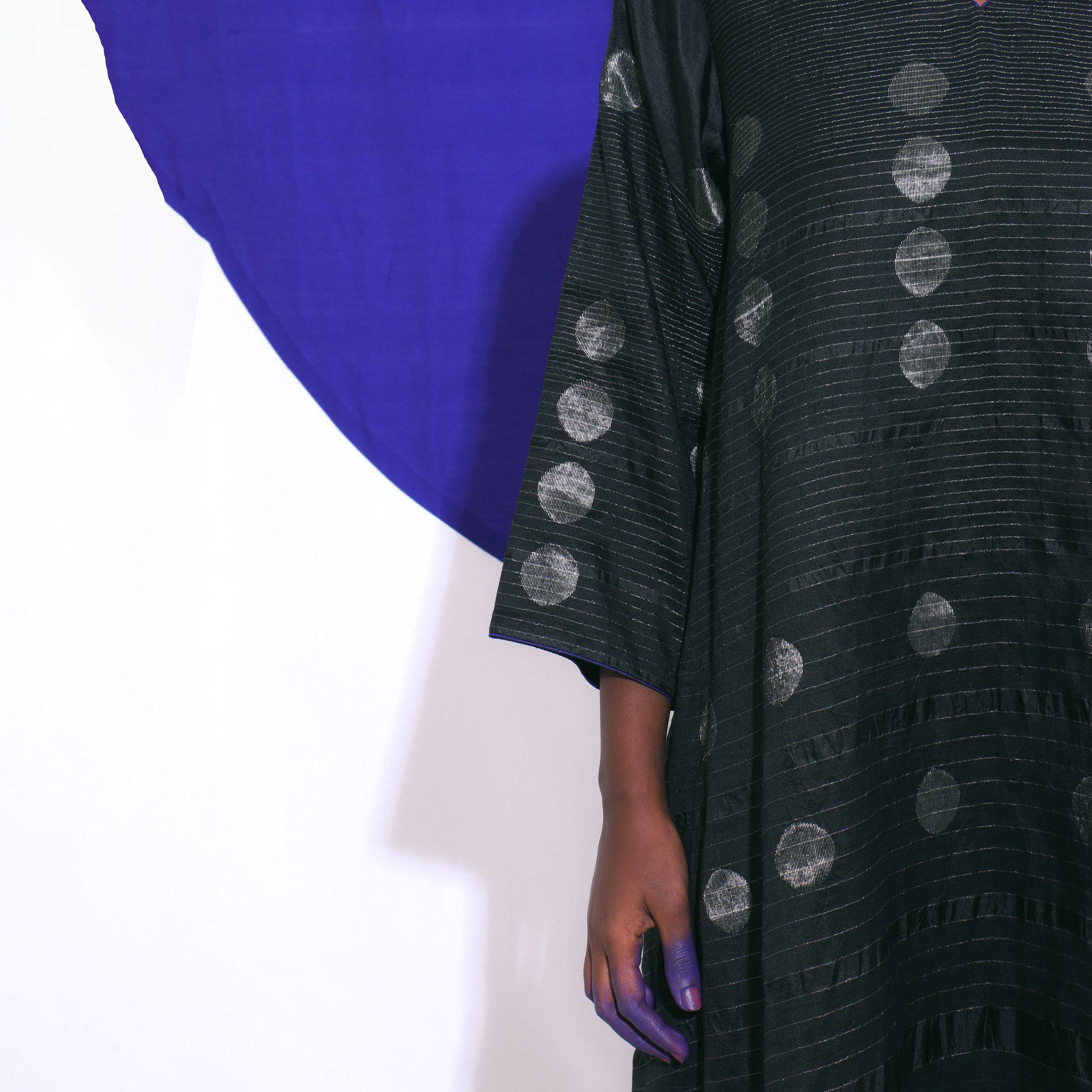 The Shoonyata Gradient Circle Flared Dress is an elegant handwoven silk piece utilizing the Jacquard Jamdani technique. It features a flattering A-line silhouette that extends to a midi length, complemented by a modest V-neckline and wide, three-quarter-length sleeves.