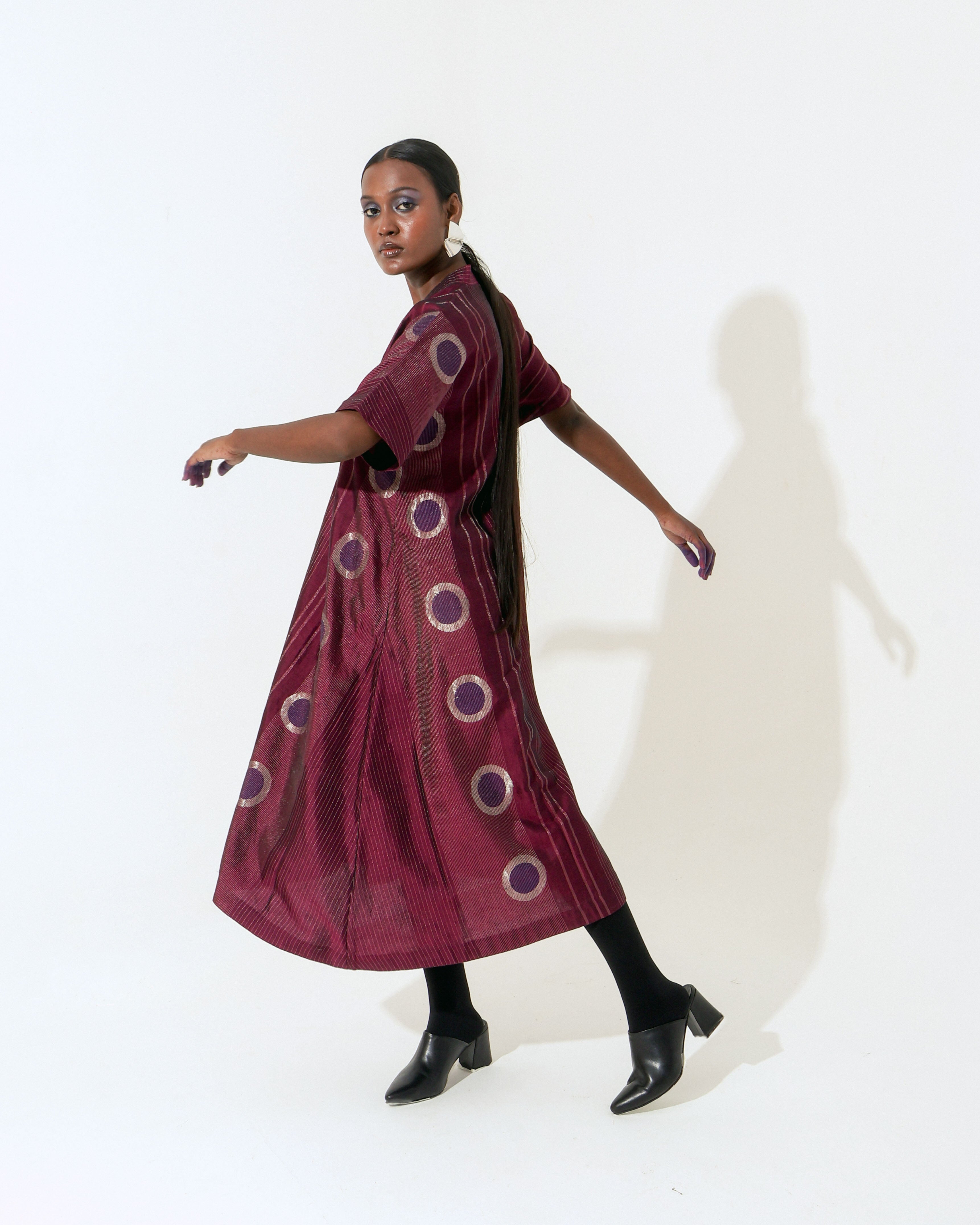 The Shoonyata Neelbindu Dress is crafted from handwoven silk, featuring the intricate Jacquard Jamdani technique with circular motifs across the fabric. Designed with a relaxed A-line silhouette that flows to a midi length, this dress exudes elegance and comfort.