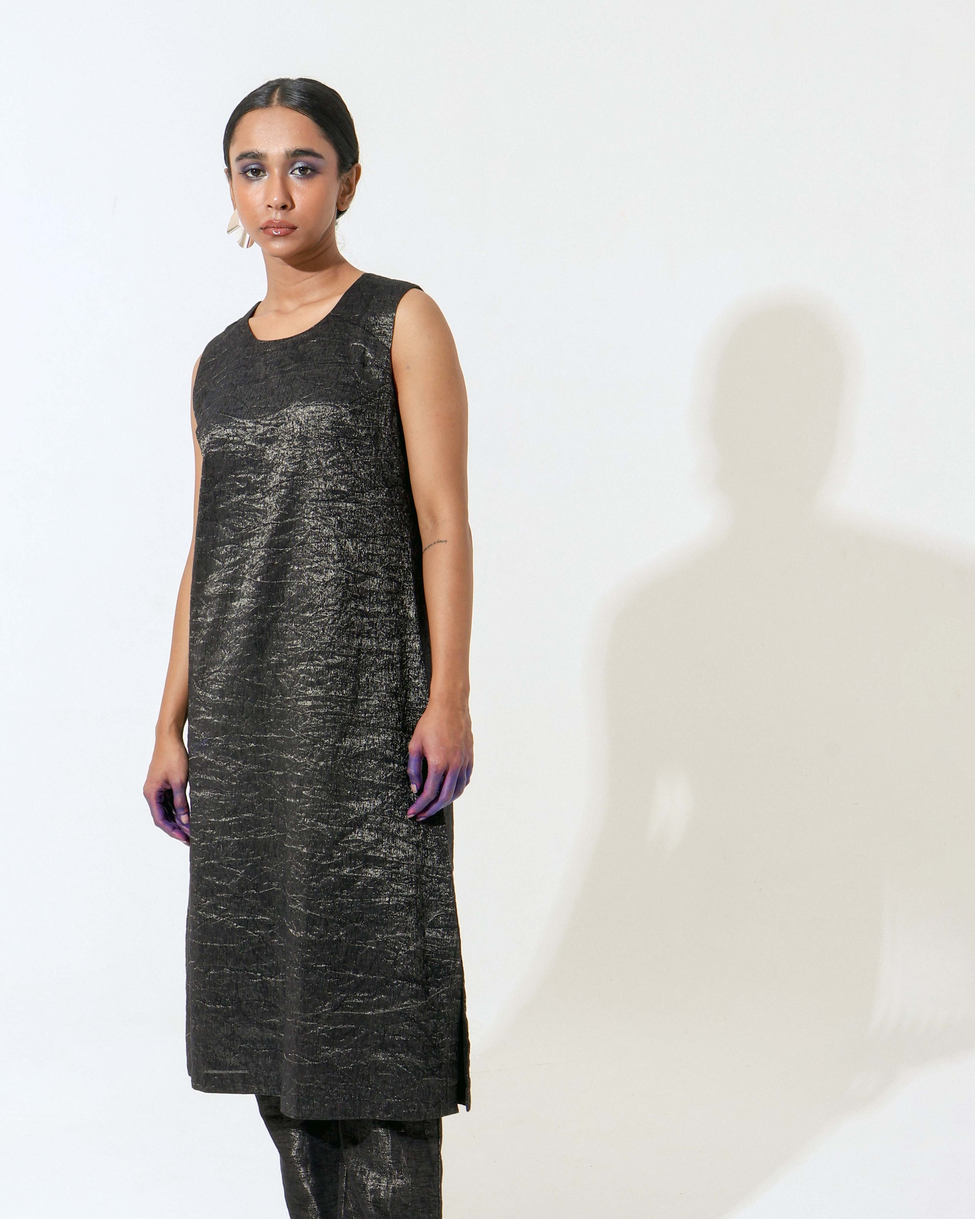 The Shoonyata Burnished Sleeveless Dress is crafted from handwoven silk. .The sleek A-line cut gently skims the body, while the sleeveless design and soft round neckline enhance its modern appeal.